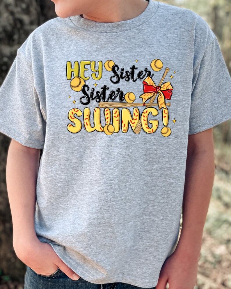 May include: A gray t-shirt with a graphic design featuring a baseball bat, baseballs, and the text "Hey Sister Sister Swing!"