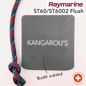 Puede incluir: Una pantalla negra empotrada para un instrumento Raymarine ST60/ST6002. La pantalla tiene una etiqueta blanca con el texto "KANGAROU'S" y un espacio para el nombre del barco.