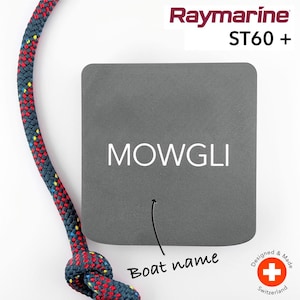 Puede incluir: Una pegatina rectangular gris con el texto "MOWGLI" en letras blancas. Debajo del texto hay una flecha que apunta al texto "Nombre del barco" escrito en negro. La pegatina está diseñada para usarse con un instrumento náutico Raymarine ST60+.