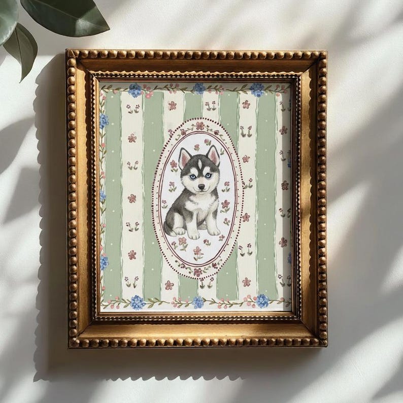 May include: A framed print featuring a watercolor illustration of a Siberian Husky puppy. The puppy is in an oval frame, set against a green and white striped background with floral accents. The frame is gold-colored.