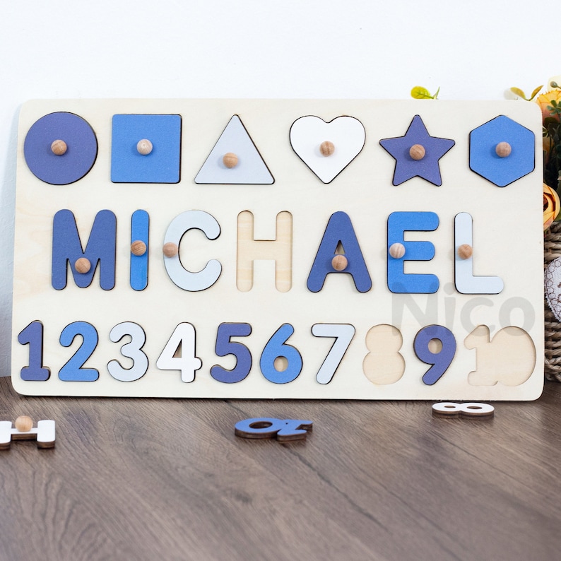 May include: Wooden puzzle board with blue and white painted shapes, letters, and numbers. The name "MICHAEL" is spelled out in blue and white letters. The numbers 1 through 10 are also included.