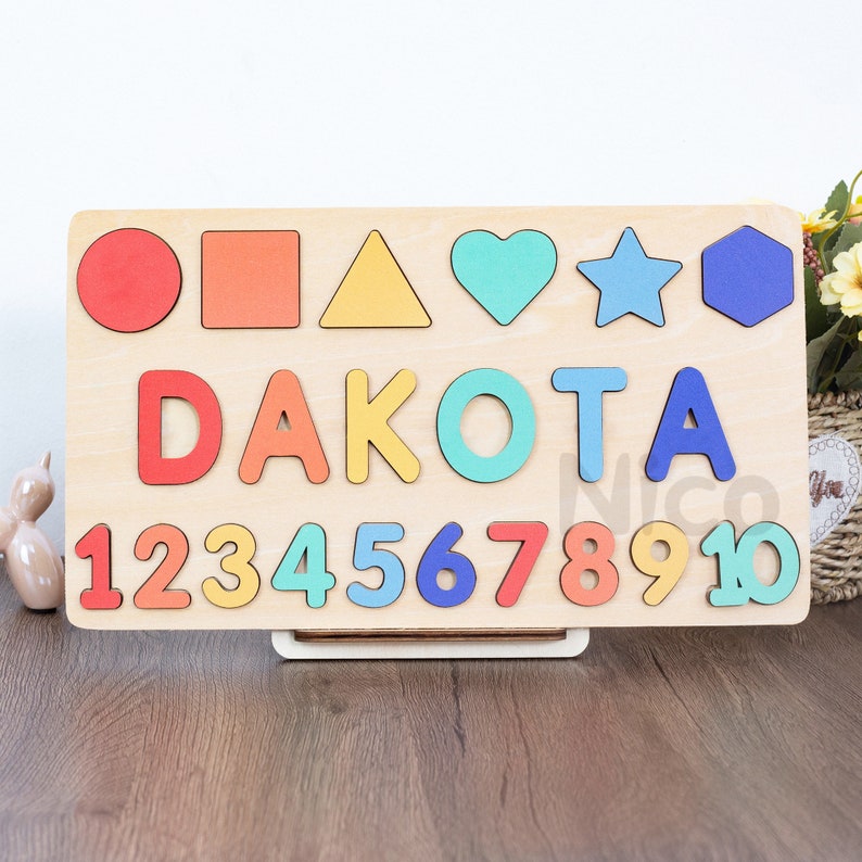 May include: Wooden puzzle board with colorful shapes, letters spelling "DAKOTA", and numbers 1 through 10.