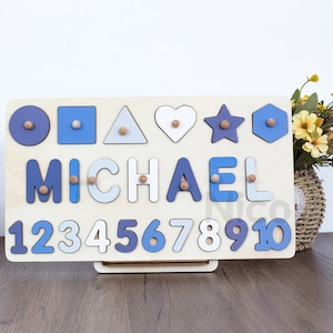 May include: A wooden puzzle board with blue and white painted letters spelling out the name "MICHAEL". The board also features a row of numbers 1 through 10, along with various shapes including a circle, square, triangle, heart, star, and hexagon.