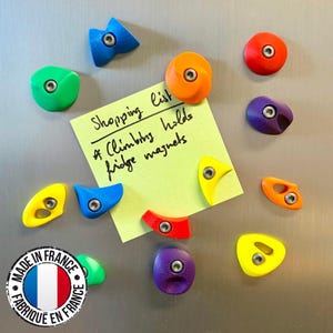 Könnte beinhalten: Bunte Kühlschrankmagnete in Form von Klettergriffen in Blau, Grün, Orange, Rot, Gelb und Lila. Ein gelber Notizzettel mit der Aufschrift "Shopping list & Climbing holds fridge magnets". Ein "Made in France"-Aufkleber befindet sich unten links.