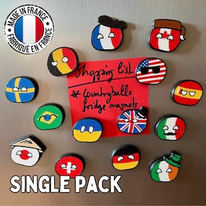 Puede incluir: Un conjunto de imanes de nevera countryball coloridos, con banderas de Francia, Estados Unidos y Reino Unido. Una nota roja dice "Shopping list" y "Countryballs fridge magnets". El texto "SINGLE PACK" está en la parte inferior.