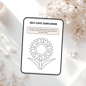 May include: A black and white coloring page with the text "SELF-LOVE SUNFLOWER" and instructions to write positive qualities and color the sunflower. The image is on a white surface with a candle and floral accents.