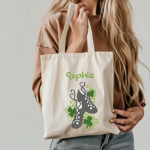 May include: A white canvas tote bag with green shamrocks and a pair of gray Irish dance shoes. The bag is personalized with the name "Sophia".