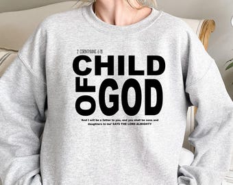 May include: A light gray sweatshirt with the text "CHILD OF GOD" in large black letters. Below the text is a quote from 2 Corinthians 6:18. The sweatshirt is a casual style.
