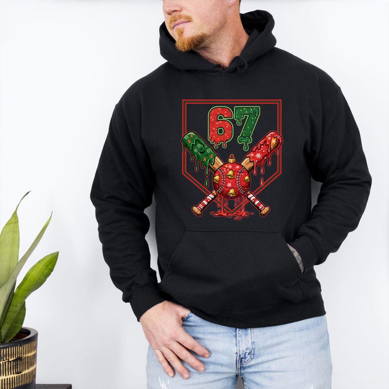 May include: Black hoodie featuring a baseball-themed graphic with the number 67 in red and green. The design includes crossed baseball bats, a baseball ornament, and a red outline.