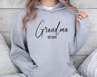 May include: Gray hooded sweatshirt with the text "Grandma EST. 2024" in black script.