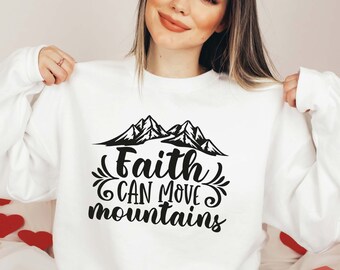 May include: White sweatshirt with the text "Faith CAN MOVE mountains" in black script and a mountain graphic. The sweatshirt is a crew neck style.