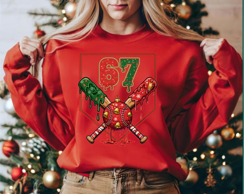 May include: Red sweatshirt with a baseball-themed graphic. The graphic features the number "67" in red and green, crossed baseball bats, and a baseball with bells. The design has a Christmas theme.