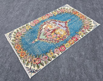 May include: A vintage Turkish rug with a blue background and a floral pattern in shades of pink, yellow, and red. The rug has a fringed edge and is made of wool.