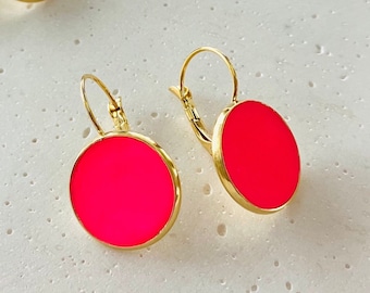 Puede incluir: Un par de pendientes de aro dorados con cabujones redondos de resina de color rosa brillante.