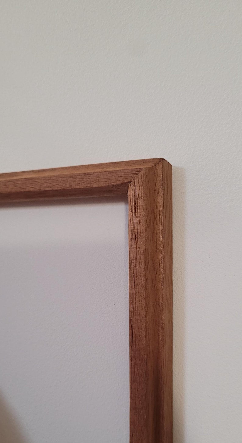 Peut inclure: Gros plan sur un coin d'un cadre photo en bois. Le cadre est en bois brun clair avec une finition lisse.