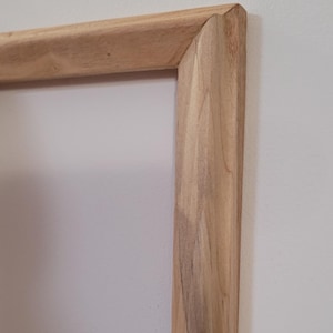 Peut inclure: Gros plan sur le coin d'un cadre en bois. Le bois est brun clair avec un grain naturel.