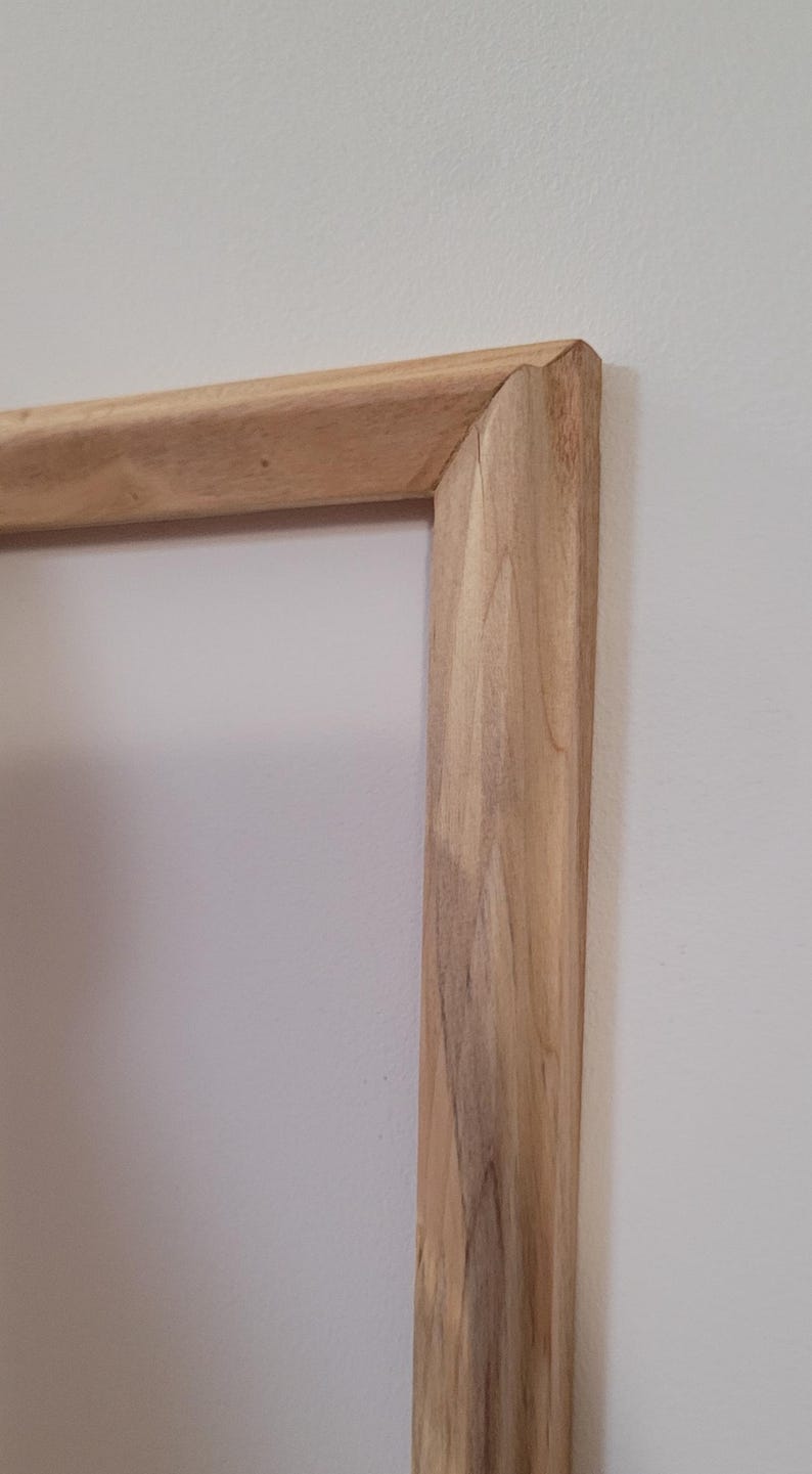 Peut inclure: Gros plan sur le coin d'un cadre en bois. Le bois est brun clair avec un grain naturel.
