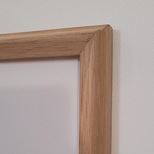 Peut inclure: Gros plan sur le coin d'un cadre photo en bois naturel. Le cadre est en bois massif avec une finition brun clair.