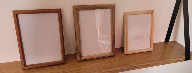 Peut inclure: Trois cadres photo en bois de diff&eacute;rentes tailles sont dispos&eacute;s sur une &eacute;tag&egrave;re en bois. Les cadres sont tous de couleur bois naturel et ont un design simple.