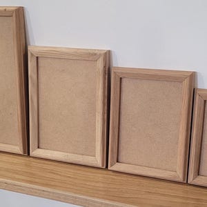 Peut inclure: Quatre cadres photo en bois de diff&eacute;rentes tailles, tous avec une finition en bois naturel. Les cadres sont dispos&eacute;s en rang&eacute;e du plus grand au plus petit, le plus grand cadre &eacute;tant &agrave; gauche et le plus petit &agrave; droite.