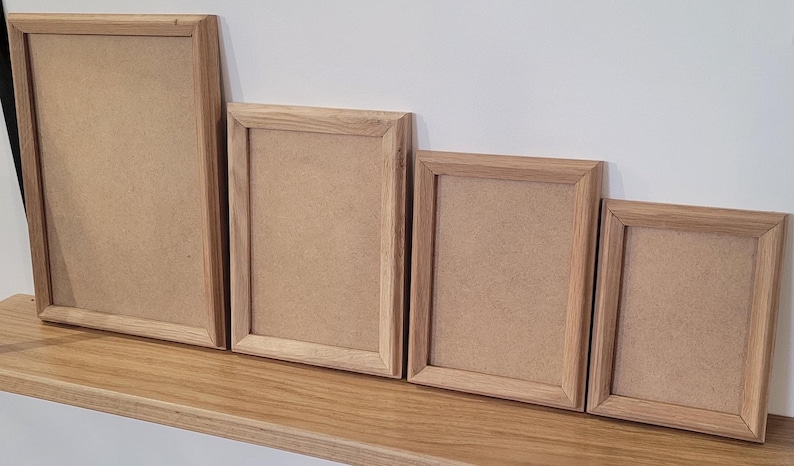 Peut inclure: Quatre cadres photo en bois de diff&eacute;rentes tailles, tous avec une finition en bois naturel. Les cadres sont dispos&eacute;s en rang&eacute;e du plus grand au plus petit, le plus grand cadre &eacute;tant &agrave; gauche et le plus petit &agrave; droite.