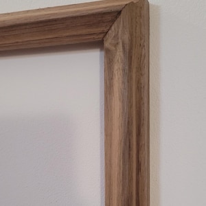 Peut inclure: Gros plan sur un cadre photo en bois avec une finition en bois naturel. Le cadre a un design simple et classique avec un bord l&eacute;g&egrave;rement sur&eacute;lev&eacute;.