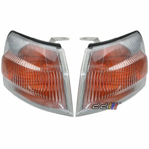 May include: A pair of clear, amber-coloured car headlights with a black trim. The headlights are designed for a car.