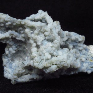 Puede incluir: Un c&uacute;mulo de &aacute;gata blanca y azul con una superficie rugosa y texturizada. La &aacute;gata tiene una variedad de formas y tama&ntilde;os, y algunas de las piezas son transl&uacute;cidas.