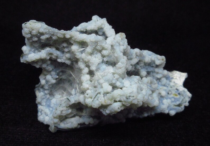 Puede incluir: Un c&uacute;mulo de &aacute;gata blanca y azul con una superficie rugosa y texturizada. La &aacute;gata tiene una variedad de formas y tama&ntilde;os, y algunas de las piezas son transl&uacute;cidas.