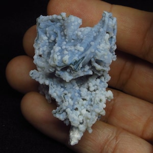 Puede incluir: Una geoda de &aacute;gata azul y blanca con una superficie rugosa y texturizada. La geoda est&aacute; cubierta de peque&ntilde;os cristales blancos.
