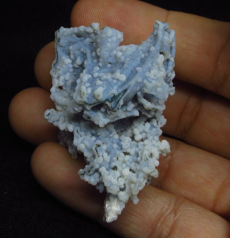 Puede incluir: Una geoda de &aacute;gata azul y blanca con una superficie rugosa y texturizada. La geoda est&aacute; cubierta de peque&ntilde;os cristales blancos.