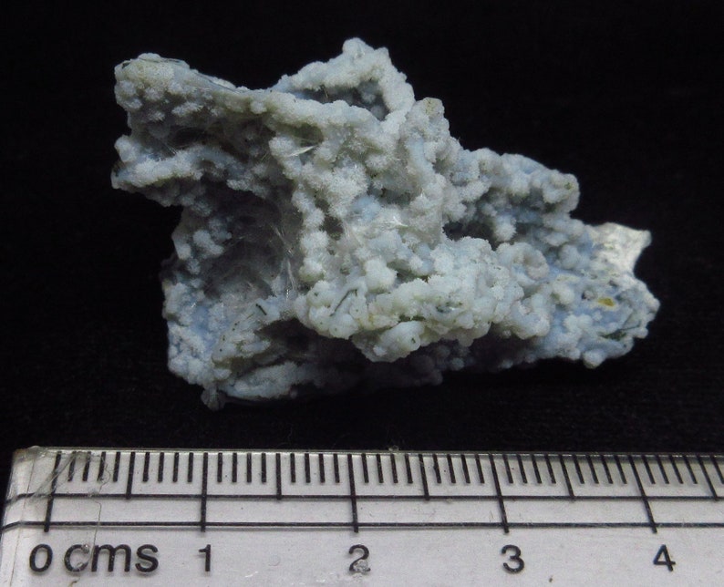 Puede incluir: Una geoda de &aacute;gata azul claro y blanco con una superficie rugosa y texturizada. La geoda mide aproximadamente 2,5 cm de ancho y est&aacute; sobre una regla.