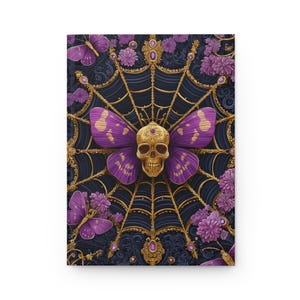 Hardcover journal featuring an ornate gothic design of a golden skull with purple butterfly wings at the center of a golden spiderweb. Surrounded by rich purple flowers, butterflies, and intricate details, all set against a dark, swirling background.