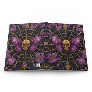Hardcover journal featuring an ornate gothic design of a golden skull with purple butterfly wings at the center of a golden spiderweb. Surrounded by rich purple flowers, butterflies, and intricate details, all set against a dark, swirling background.
