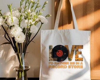 Op de afbeelding: Witte canvas tote bag met een vintage platenspeler ontwerp en de tekst "LOVE I'D RATHER BE IN A RECORD STORE".