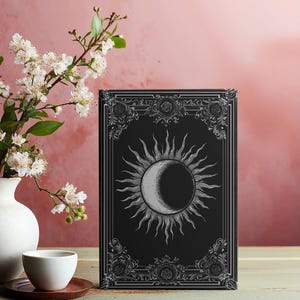 May include: A black journal with a sun and moon design on the cover. The journal has 150 lined pages and a matte finish. It measures 5.75 inches by 8 inches.