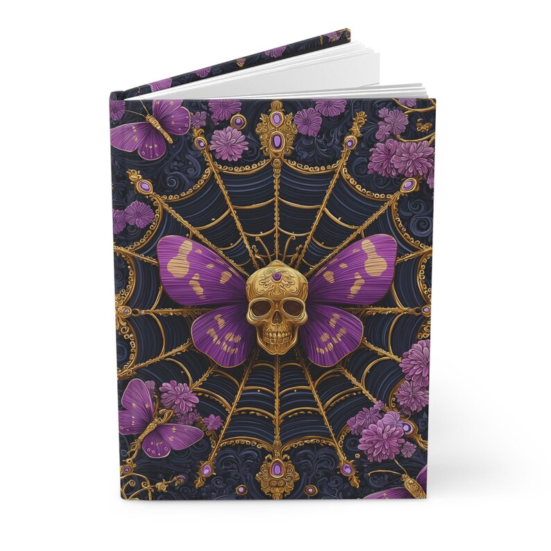 Hardcover journal featuring an ornate gothic design of a golden skull with purple butterfly wings at the center of a golden spiderweb. Surrounded by rich purple flowers, butterflies, and intricate details, all set against a dark, swirling background.