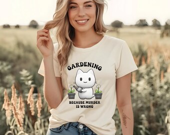 May include: Cream-colored t-shirt with the text "GARDENING" above a cartoon cat watering plants. Below the cat, the text reads "BECAUSE MURDER IS WRONG." The shirt is paired with blue jeans.