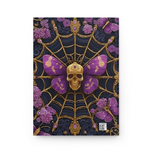 Hardcover journal featuring an ornate gothic design of a golden skull with purple butterfly wings at the center of a golden spiderweb. Surrounded by rich purple flowers, butterflies, and intricate details, all set against a dark, swirling background.
