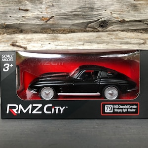 May include: A black 1963 Chevrolet Corvette Stingray Split Window scale model car in its original packaging. The model car is black with silver wheels and is displayed in a black box with the RMZ City logo and the number 79.