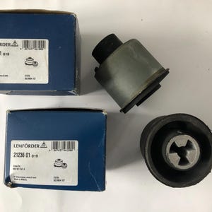 May include: Two blue boxes and two automotive parts are displayed on a white surface. The boxes have white labels with black text and a barcode. The automotive parts are black and gray, with a cylindrical shape.