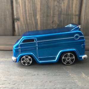 May include: A die-cast blue van toy with silver accents, including a spoiler and detailed wheels. The toy van is a miniature replica of a classic vehicle, with a glossy finish and a retro design.