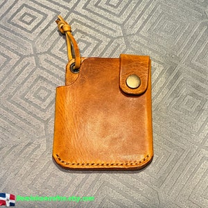 May include: A brown leather wallet with a flap closure and a metal button. The wallet has a stitched edge and a loop for attaching a key chain.