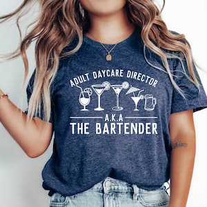 May include: A navy blue t-shirt with white text that reads "Adult Daycare Director A.K.A. The Bartender" and a row of white cocktail drink icons.