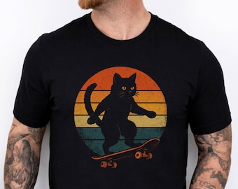May include: Black t-shirt featuring a retro design of a black cat skateboarding. The cat is silhouetted against a sunset-colored circle with orange, yellow, and teal stripes. The skateboard has orange wheels.