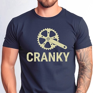 May include: A navy blue t-shirt with a vintage-style illustration of a bicycle crankset and the word "CRANKY" in a distressed font.