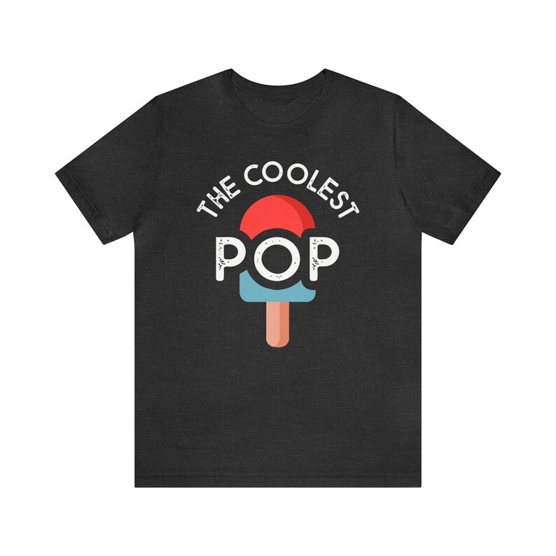 Puede incluir: Camiseta gris oscuro con el texto "THE COOLEST POP" sobre un gr&aacute;fico de paleta roja y azul. La paleta tiene un palo marr&oacute;n. La camiseta est&aacute; hecha de un material suave.