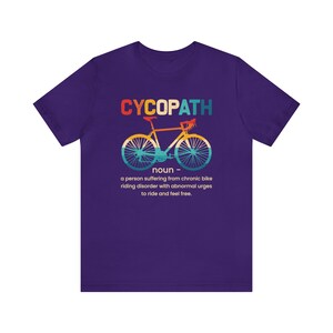May include: Purple t-shirt with a graphic of a bicycle and the text "CYCOPATH" defined as "a person suffering from chronic bike riding disorder with abnormal urges to ride and feel free."