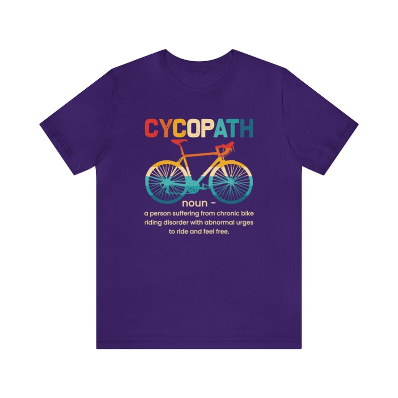 May include: Purple t-shirt with a graphic of a bicycle and the text "CYCOPATH" defined as "a person suffering from chronic bike riding disorder with abnormal urges to ride and feel free."