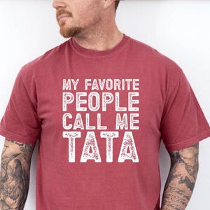May include: A red t-shirt with white text that reads "My Favorite People Call Me Tata".